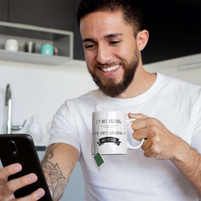 A Photograph of a man with a mug with I'm Not Arguing I'm Explaining Why I'm Right printed on the front