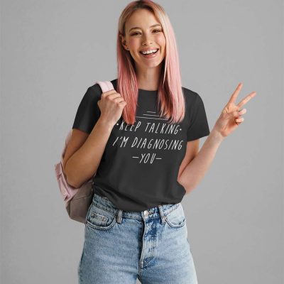 A Photo of a lady with pink hair wearing a black t shirt with the words Keep Talking I'm Diagnosing You printed on the front