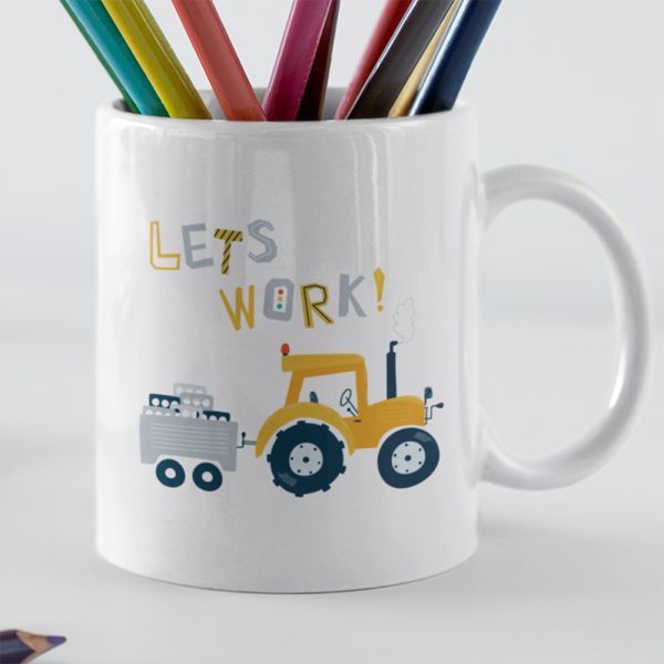 A closeup of a mug with the colourful words Lets Work Printed on it alsong with a yellow hand drawn tractor and trailer