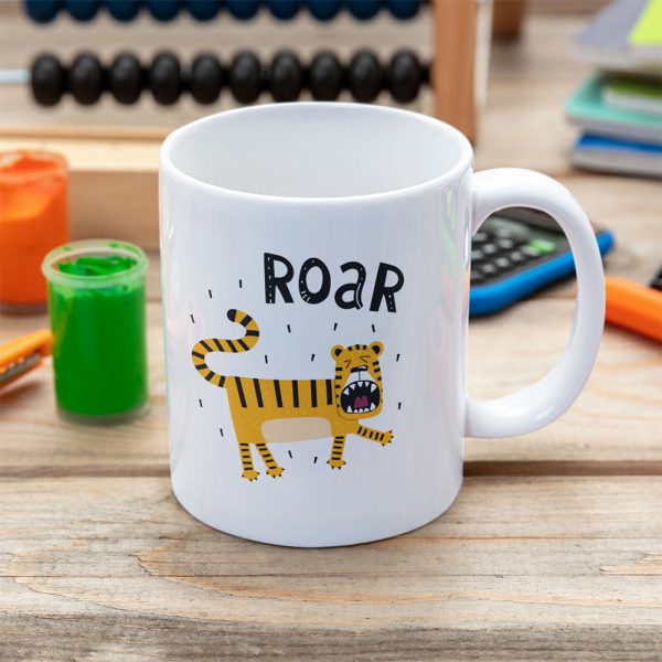 A photograph of a kids table with a mug with a cute cartoon tigher and the word Roar printed above it's head