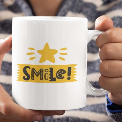 A close up photograph of a mug with a bright yellow star and the colourful words smile printed on it