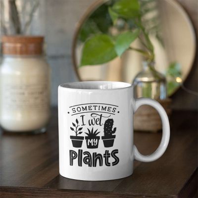 A photo of a mug with the words Sometimes I Wet My Plants printed on it along with images of potted plants