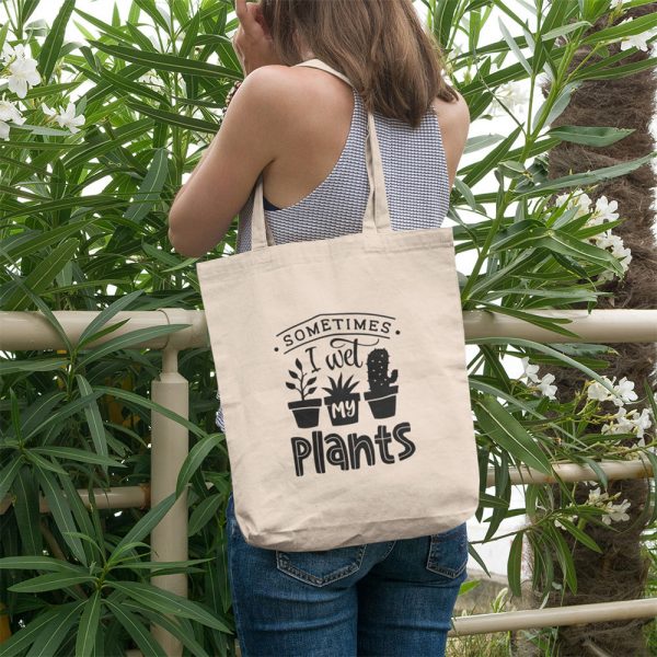 A photograph of the back of a lady she has a tote bag over her shoulder and it reads Sometimes I Wet My Plants