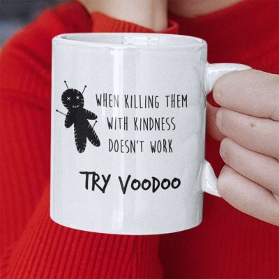 A Closeup of a mug with a picture of a voodoo doll and the words When Killing Them With Kindness Doesn't Work Try Voodoo printed on it