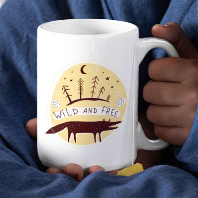 A Photograph of a mug with the words wild and free printed on it, surrounded by Scandinavian cave art inspired wolves and trees and moons